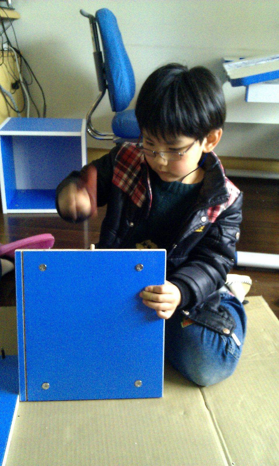 A young Tianqiqi fastening a blue furniture panel