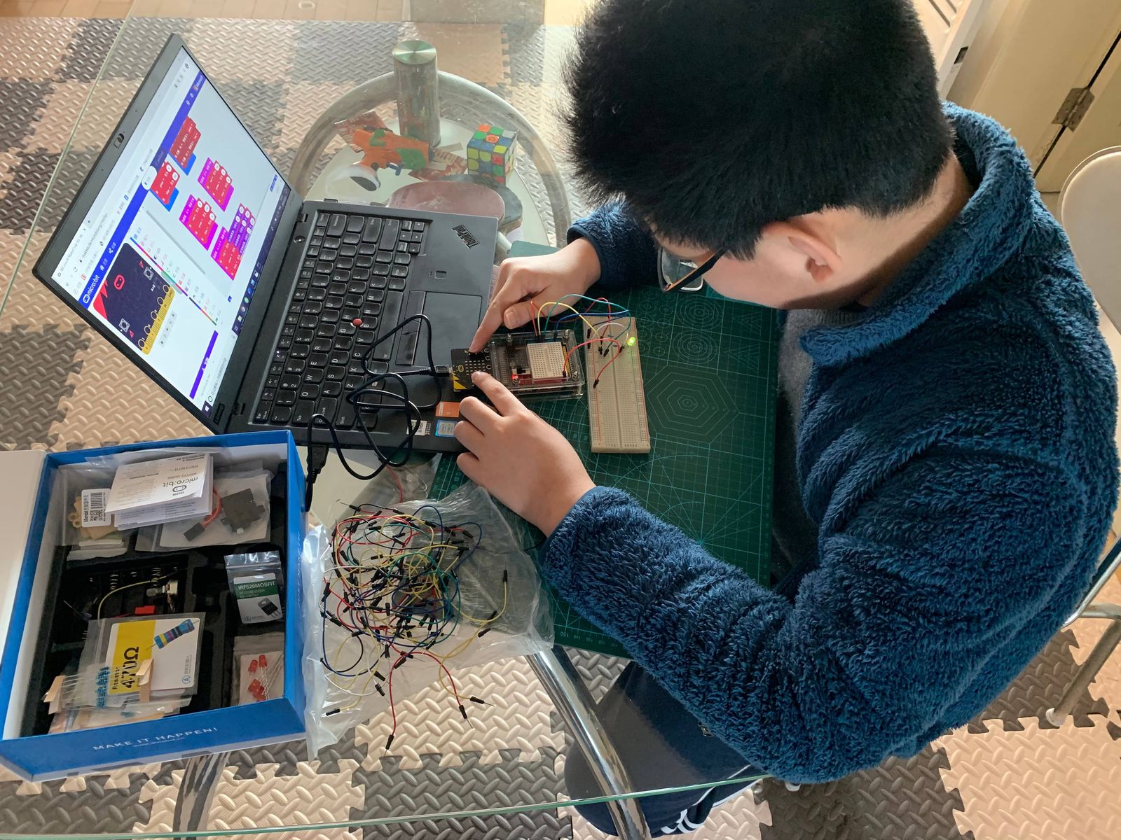 Tianqiqi programming a microcontroller from a laptop beside a breadboard