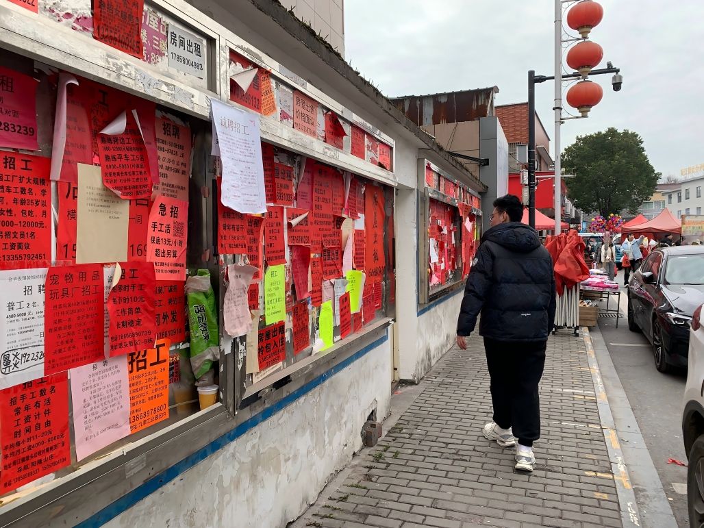 A street wall covered with red job and rental notices