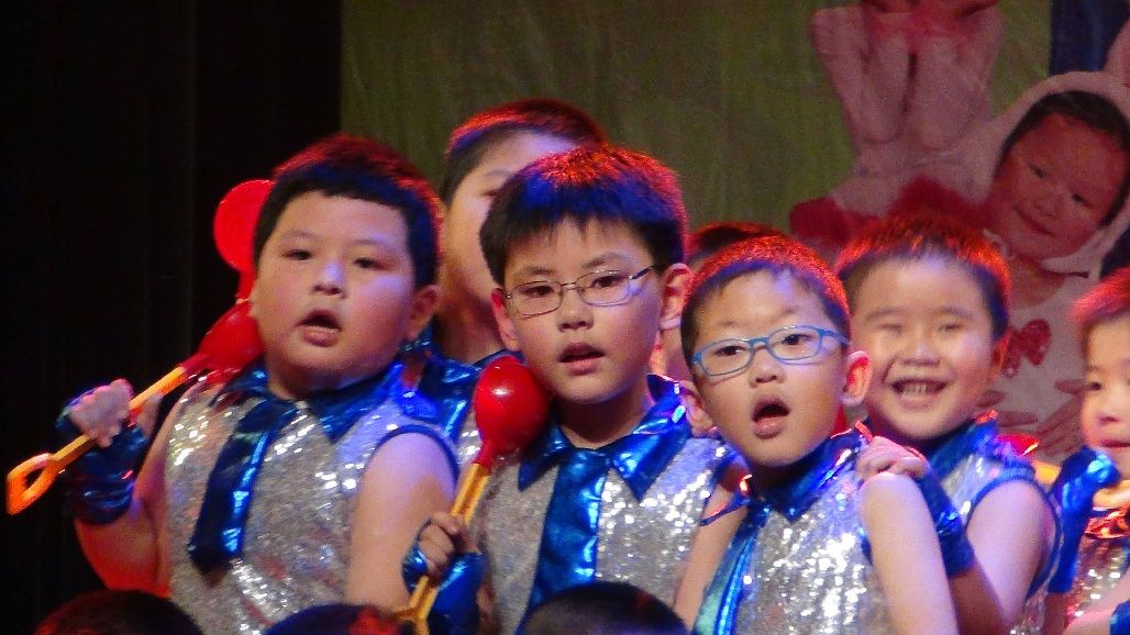 Close view of children singing on stage in matching costumes