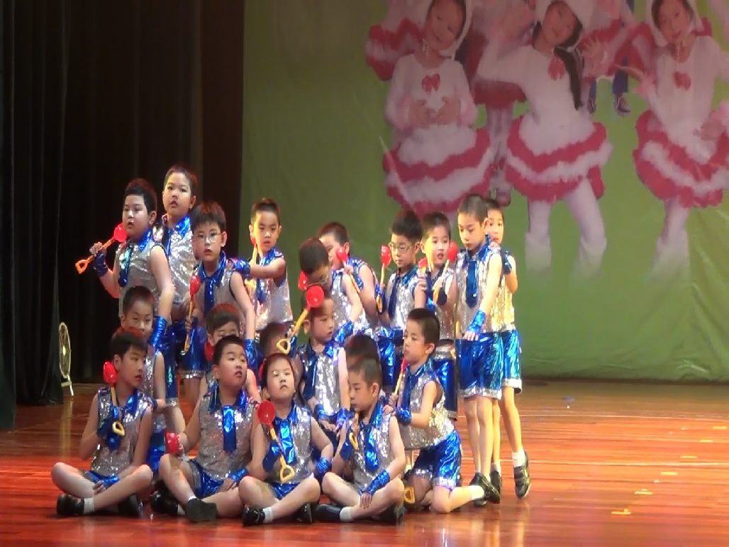 A full children's ensemble on a wooden stage